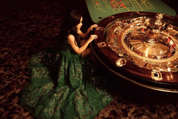 A woman in a luxurious green gown next to an ornate roulette wheel, capturing the upscale casino mood of CD45.