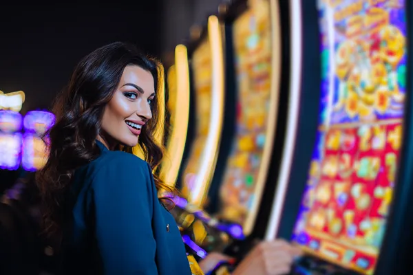 A woman smiling by bright slot machines showing lucky symbols, showcasing the exciting slot offerings at CD45.